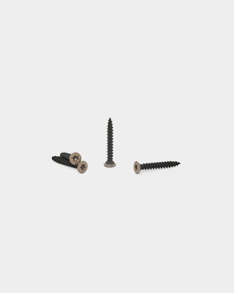 WoodUpp image shows four WoodUpp wood screws on a white background: three black, coarse-threaded screws with bronze-colored countersunk star-drive heads—two lying together, one on its side—and a fourth screw standing upright in the center, highlighting thread profile and finish.